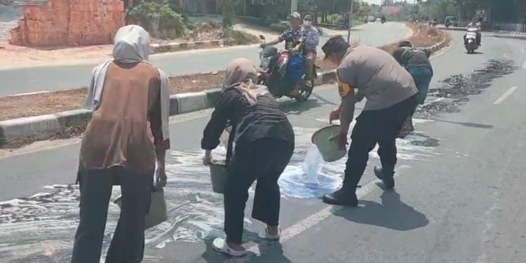 Sigap Cegah Kecelakaan, Bhabinkamtibmas Bersama Damkar dan Masyarakat Bersihkan Tumpahan Minyak di Jalan